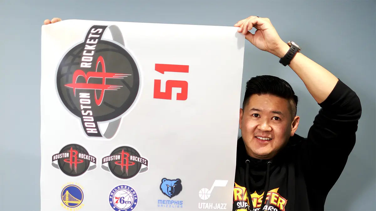 Person holding a large DTF gang sheet transfer film with multiple logos arranged for batch printing
